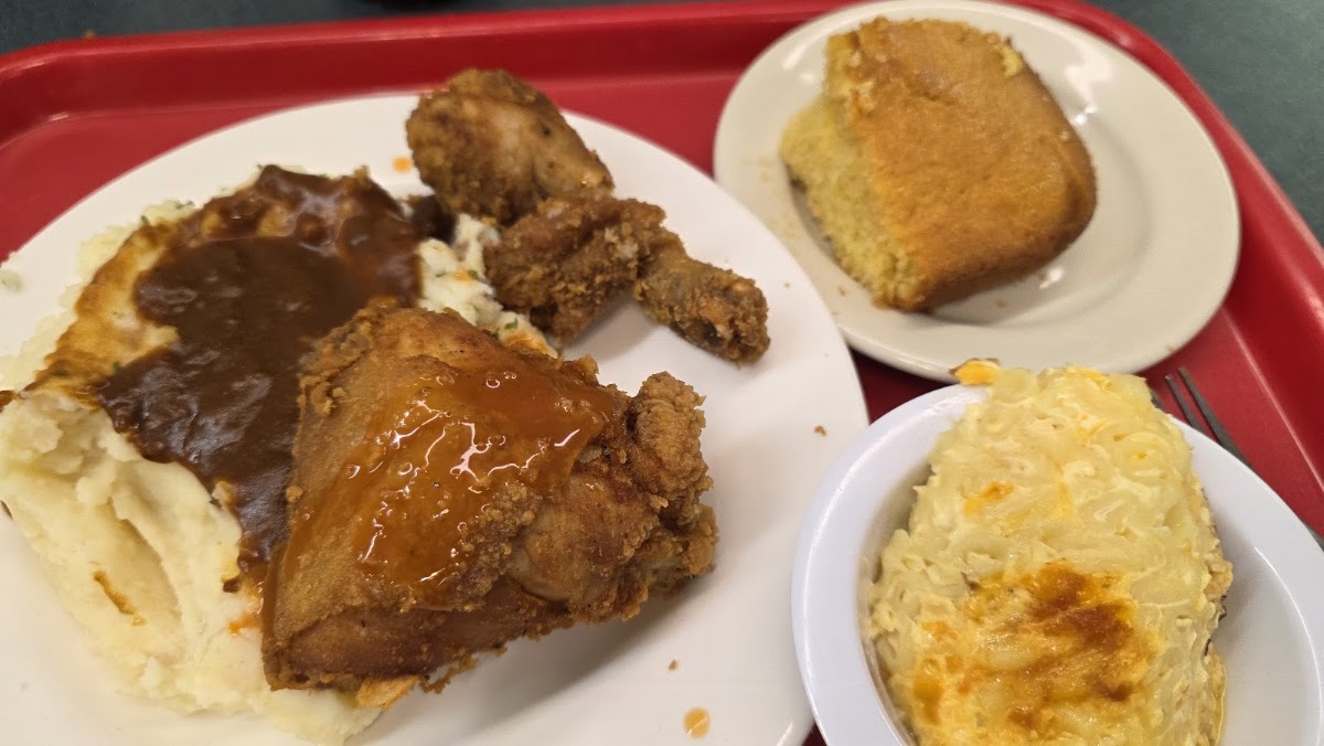 Smothered pork chop with mashed potatoes, mac and cheese and cornbread